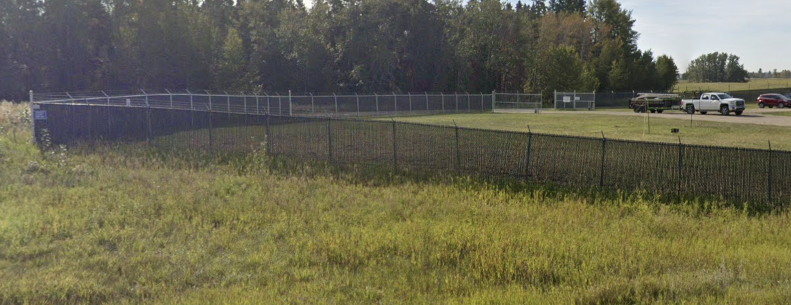 Security fencing around a grassy area with a security gate visible in the background.