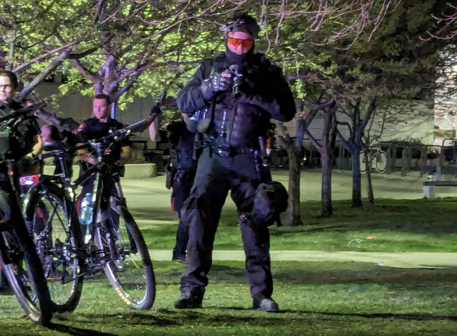 Police Officer in light armor and helmet looks down to inspect a photograph in a digital camera.