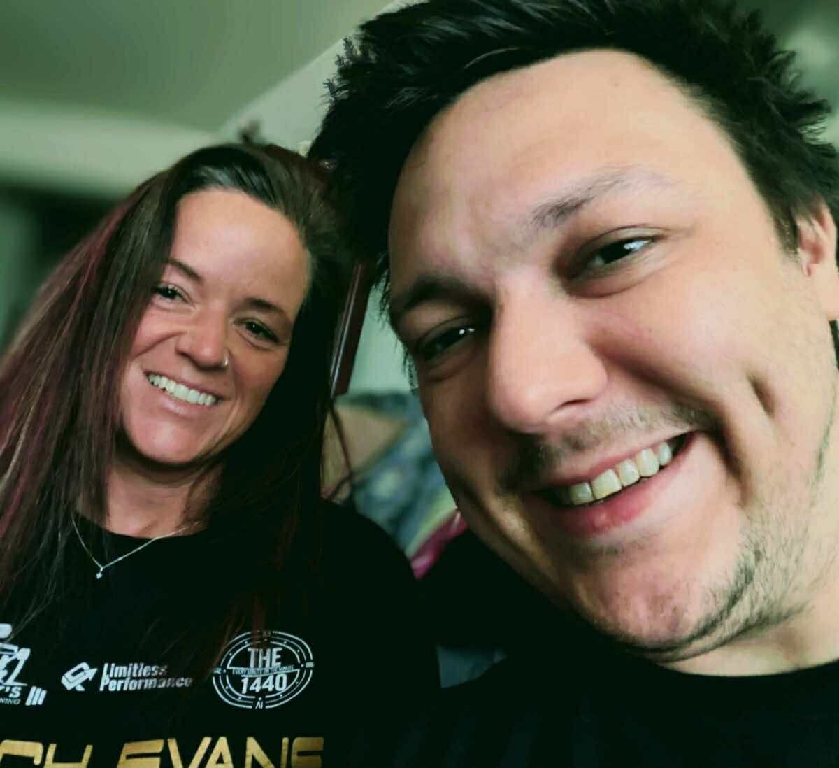 A woman with shoulder-length brown hair and man with short hair smile at the camera from close up.