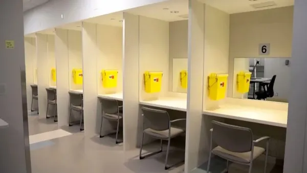 6 tidy booths with mirrors, chairs, and sharps disposal bins in a row in a small room.